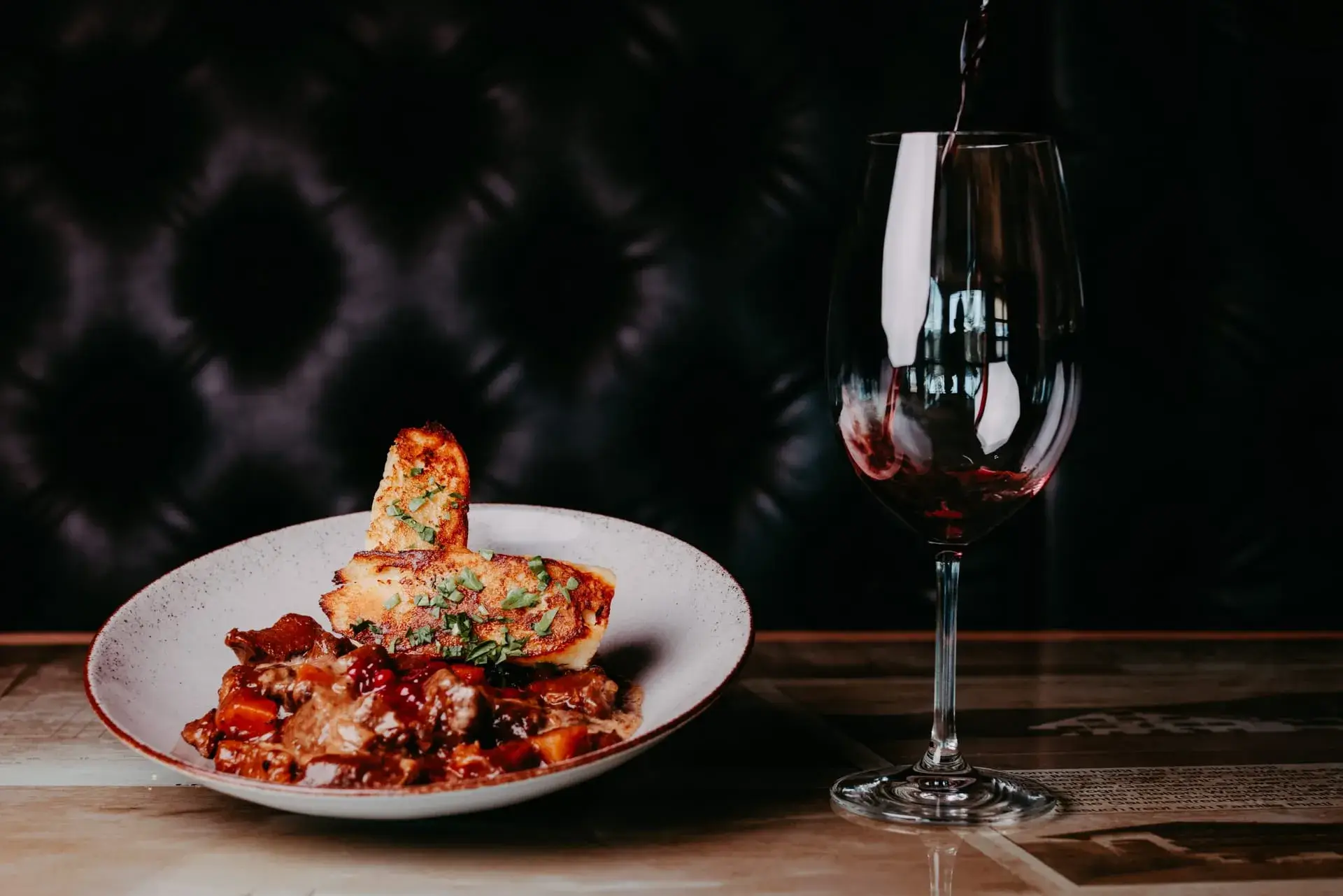 Fein angerichtetes Gourmet-Gericht mit Glas Rotwein im Restaurant Greenvieh in Mieming, Tirol