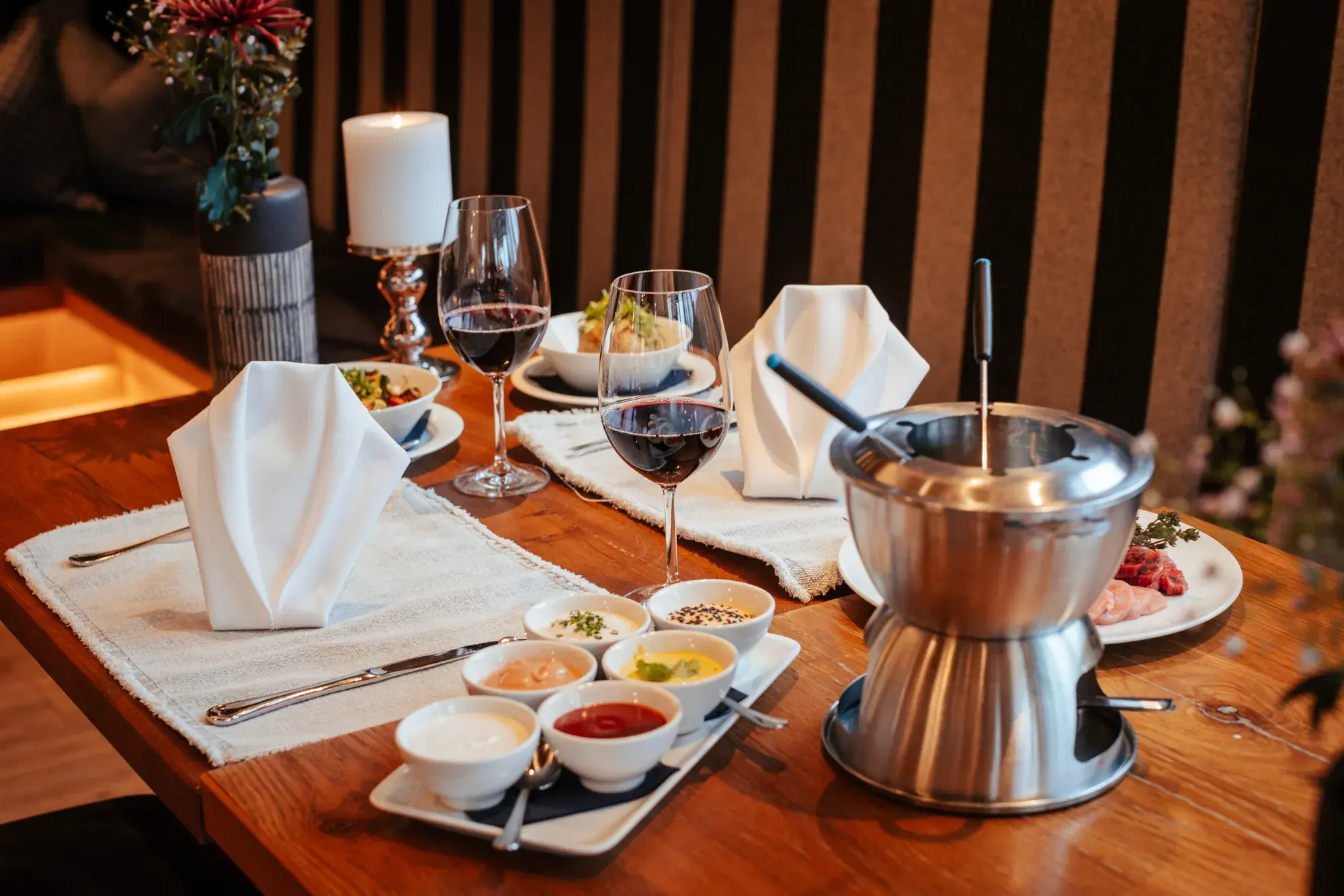 Fondue Abend im Greenvieh – gedeckter Tisch mit Bouillon-Fondue, hausgemachten Dipsaucen und Rotwein in Mieming, Tirol