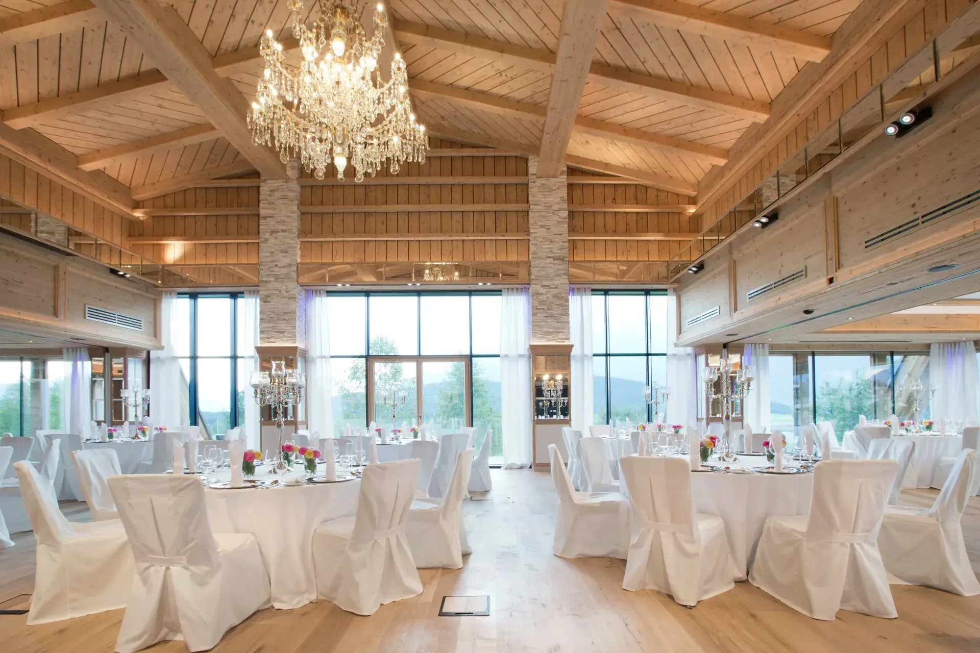 Festively set wedding hall with chandelier and chair covers in the Greenvieh Chalet, Mieming