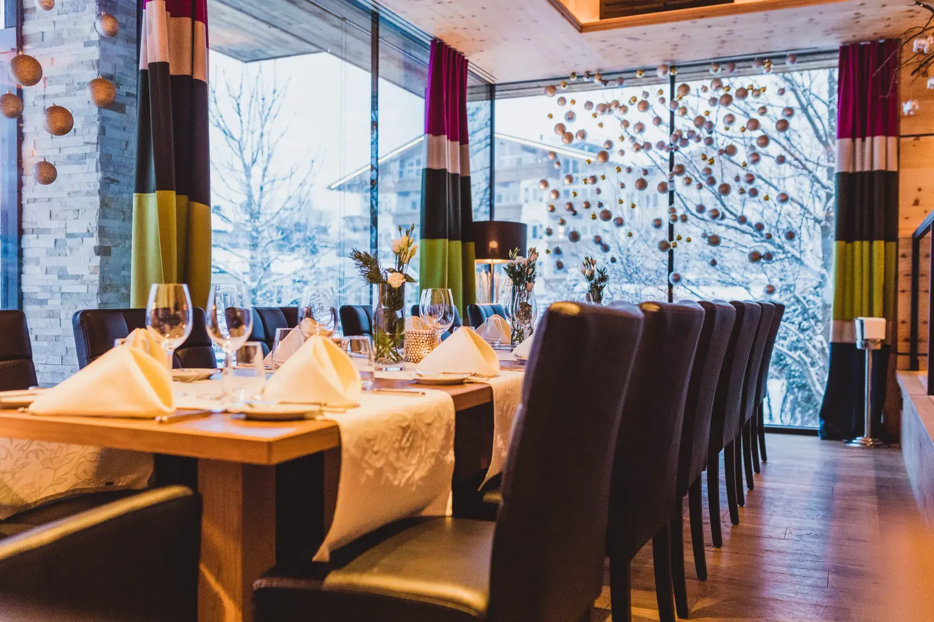 Restaurant des Greenvieh im Winter: festlich eingedeckter Tisch vor verschneiten Fenstern in Mieming, Tirol