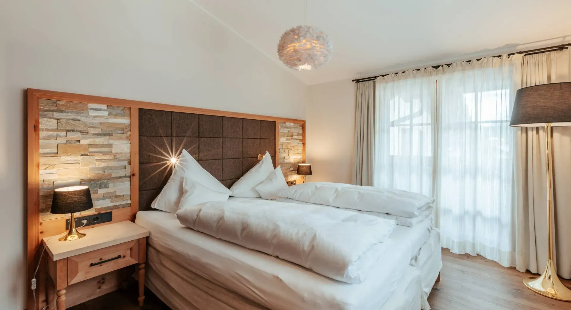 Cosy double room with wood and natural-stone headboard at the Biohotel Schweitzer in Mieming
