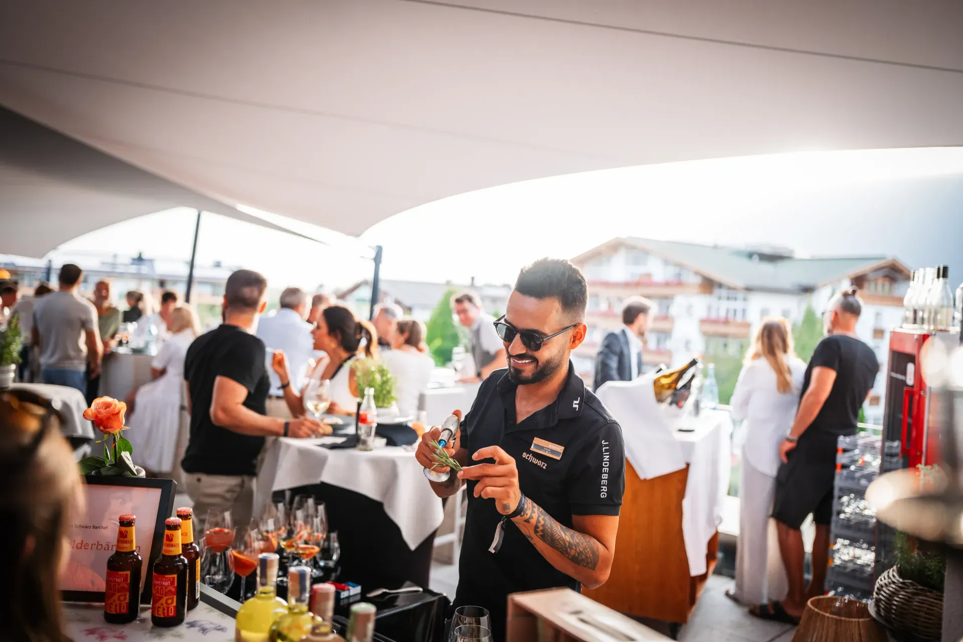 Bartender mixing Aperol Spritz at the get-together on the sunny Greenvieh rooftop terrace