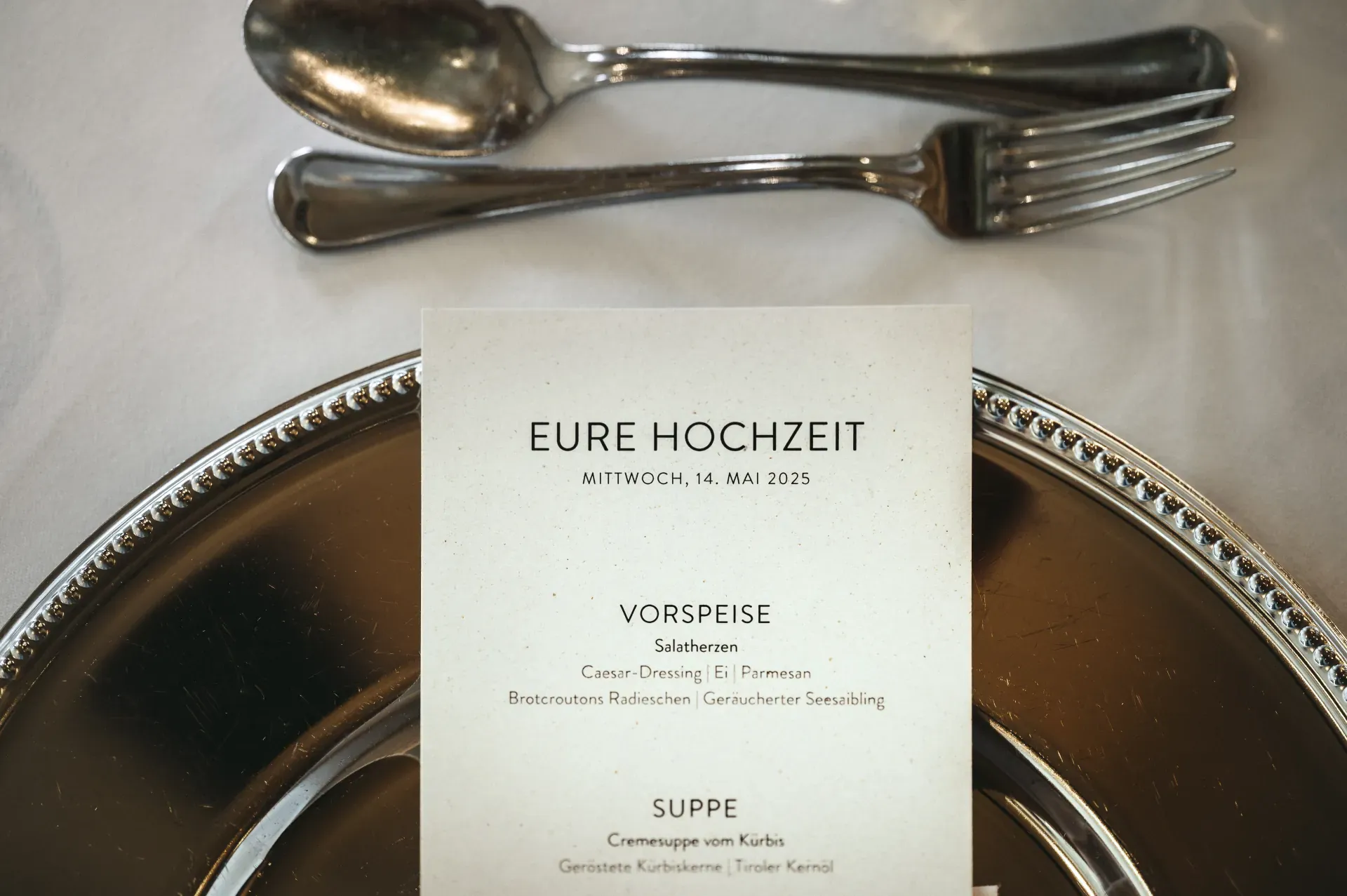 Elegant place setting with silver charger and wedding menu card at the Greenvieh